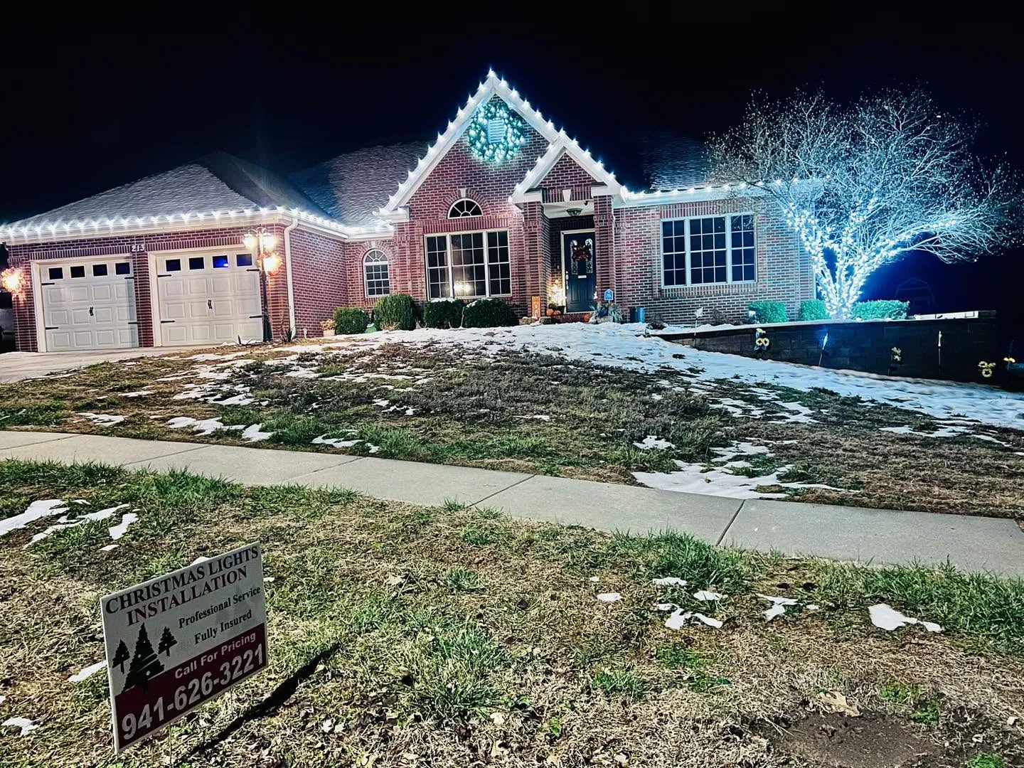 Professional white holiday lighting installed on a brick home and tree
